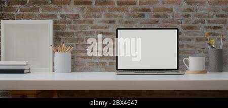 Vista ravvicinata del tavolo da ufficio con computer portatile, strumenti di  pittura e decorazioni su scrivania bianca con parete in mattoni Foto stock  - Alamy