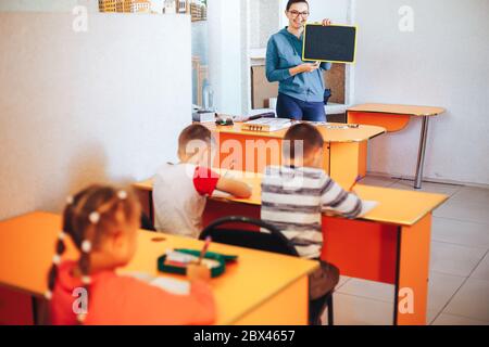 L'insegnante insegna ai bambini in classe esibisce una piccola tavola Foto Stock