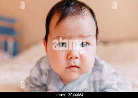 Baby girl sul suo stomaco. Ricerca con espressioni di sorpresa. Foto Stock