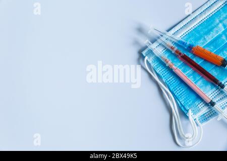 Siringhe con maschere mediche su sfondo chiaro. Il concetto del tema medico. È presente un'area per lo spazio di copia Foto Stock