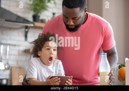 Carina bambina che tiene il suo piatto e che guarda sorpreso con la sua bocca aperta Foto Stock