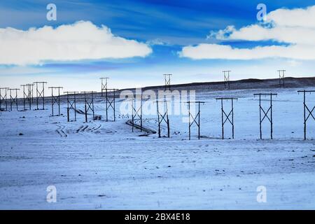 Le linee elettriche ad alta tensione di vecchia costruzione (pali di legno) passano attraverso le colline innevate del Caucaso Foto Stock