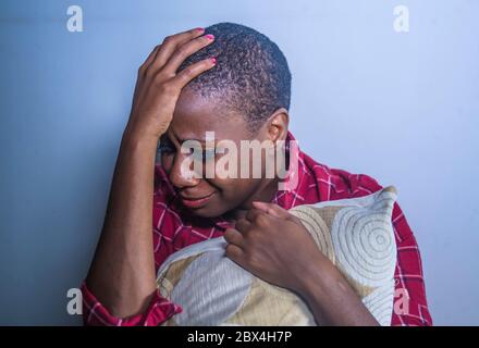 Stile di vita indoor ombreggiato ritratto di giovane triste e depresso donna afro americana nera seduta a casa pavimento sensazione disperata e preoccupata sofferenza pa Foto Stock