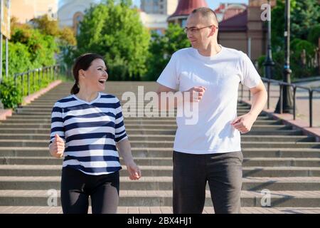 Coppia che corre sulle scale in città, uomo maturo e donna insieme Foto Stock
