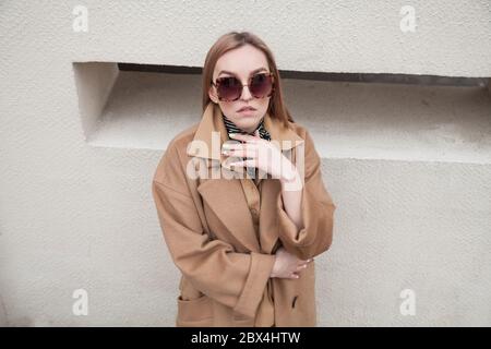 Dettaglio di un primo piano di un cappotto di lana femminile. Giovane ragazza adulta in elegante cappotto all'aperto. Cappotto promozionale da donna. Giovane donna di moda capelli giusti Foto Stock