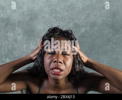 Giovane pazza disperata e ansiosa donna nera afroamericana sentendosi stressata e tormentata in un'intensa e drammatica espressione facciale isolata su stud Foto Stock