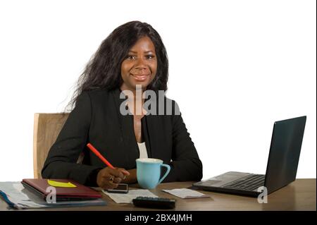 Giovane felice e attraente donna di affari afro americana nera che lavora alla scrivania del calcolatore d'ufficio sorridente riuscito che pone l'azienda come efficiente ed exp Foto Stock