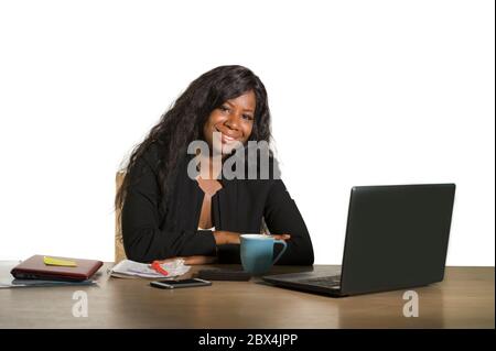 Giovane felice e attraente donna di affari afro americana nera che lavora alla scrivania del calcolatore d'ufficio sorridente riuscito che pone l'azienda come efficiente ed exp Foto Stock