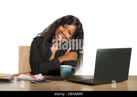 Giovane felice e attraente donna di affari afro americana nera che lavora alla scrivania del calcolatore d'ufficio sorridente riuscito che pone l'azienda come efficiente ed exp Foto Stock