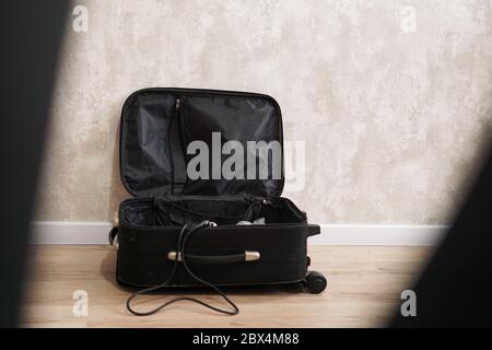Aperta valigia vuota nera per diverse cose su sfondo grigio. Concetto di preparazione del viaggio Foto Stock