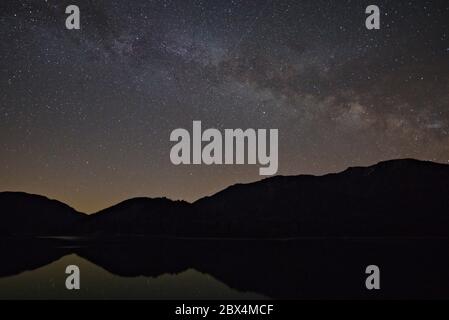 Via Lattea nella regione montana che si riflette nel lago Sylvenstein, Baviera, Germania Foto Stock