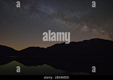 Via Lattea nella regione montana che si riflette nel lago Sylvenstein, Baviera, Germania Foto Stock