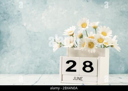 Calendario cubo bianco per giugno decorato con fiori margherita su sfondo blu con spazio copia Foto Stock