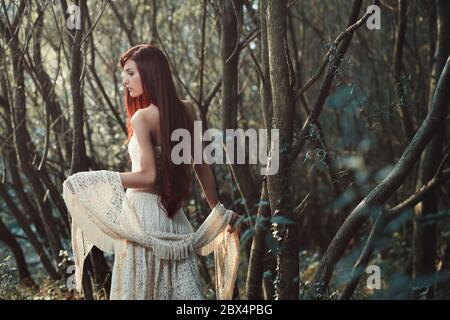 Bella donna rossa dei capelli che posa nei boschi . Etereo e romantico Foto Stock