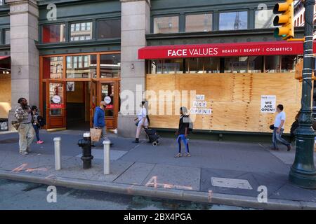 New York, 3 giugno 2020. La gente passa davanti a un negozio di cosmetici e varietà con finestre chiuse e cartelli "We Are Open" dopo una recente ondata di furti e saccheggi organizzati in altre parti della città. Face Values Store si unisce ad altre aziende in tutta la città, spaventate dai saccheggiatori, aprendo le finestre e le porte come misura precauzionale e rimanendo aperte agli affari durante la crisi covid-19. I numerosi negozi chiusi in tutta la città inviano un messaggio di disperazione e disperazione a molti non abituati a vedere così tanti negozi chiusi in una città normalmente vivace e trafficata. Foto Stock