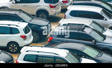 Auto bianca e nera parcheggiata in un parcheggio in cemento del centro commerciale in vacanza. Vista aerea dell'area parcheggio all'aperto del centro commerciale. Settore automobilistico Foto Stock