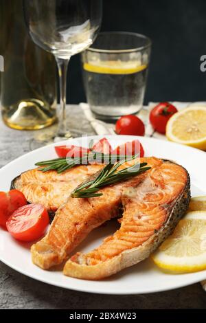 Composizione con gustoso salmone alla griglia su sfondo grigio, primo piano Foto Stock
