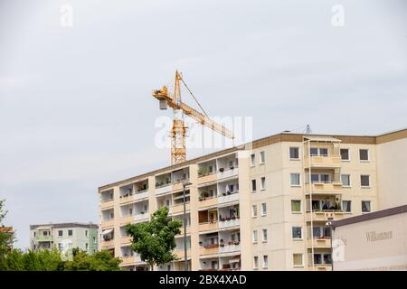 Heidenau, Germania. 04giugno 2020. Una gru si trova dietro un edificio residenziale a Heidenau, in Sassonia, con il suo lungo braccio. Dietro la casa, l'edilizia sociale viene demolita, anche se è necessaria per il mercato immobiliare nella conurbazione intorno alla capitale di stato Dresda. Credit: Daniel Schäfer/dpa-Zentralbild/ZB/dpa/Alamy Live News Foto Stock