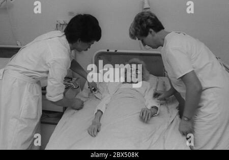 Berlino / Prenzlauer Berg / Salute / GDR / 3 / 1990 Vecchia donna in ospedale Prenzlauer Berg, reparto per pazienti cronicamente malati. La camera dispone di 8 letti. Infermieri. // anziani / cura / anziani / *** Città *** Germania Est / Germania Comunista / Ospedale sanitario a Prenzlauer Berg, quartiere di Berlino Est. [traduzione automatizzata] Foto Stock