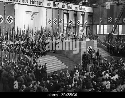 Adolf Hitler durante un discorso in una sala della fabbrica di carri Weitzer a Graz. Dopo che l'Austria fu annessa al Reich tedesco, il dittatore nazionalsocialista visita la capitale della Stiria. Sullo sfondo si legge: "Una nazione, un leader, un popolo". Foto Stock