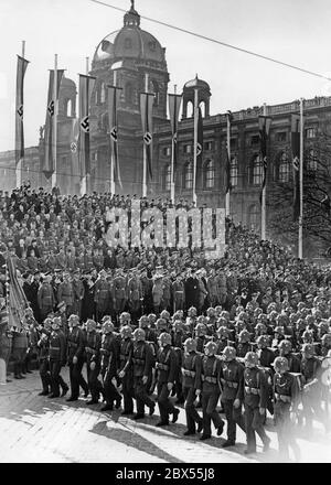 Marcia dei soldati di fronte ad Adolf Hitler durante la parata militare sulla Heldenplatz a Vienna. La parata si svolge nel corso delle celebrazioni per l'annessione dell'Austria al Reich tedesco. I soldati austriaci indossano già l'emblema nazionale tedesco sui loro caschi e uniformi in acciaio. Foto Stock