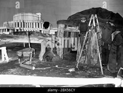 Preparazione della mostra 'il Paradiso sovietico' a Lustgarten di Berlino: I lavoratori costruiscono un dugout, accanto ad esso è una foto di un'opera a Minsk, che dovrebbe simboleggiare i contrasti in modo propagandistico. Foto Stock