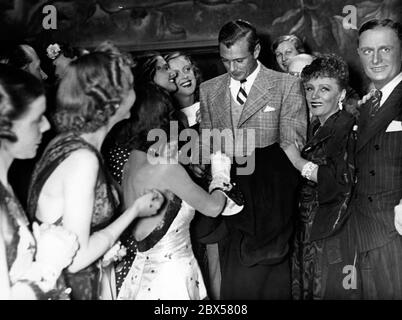 Gary Cooper durante una visita al parco cinematografico UFA di Babelsberg, vicino a Berlino. Dà autografi ai ballerini. Foto Stock