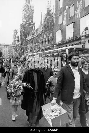 I politici verdi Christian Magerl (davanti a destra) e Ruth Paulig (davanti a sinistra, dietro di loro Christine Scheel) sulla strada da un raduno sulla Marienplatz alla riunione costituente del parlamento di Stato al Maximilianeum. In mano, egli tiene un pacchetto di fieno contaminato dal disastro di Chernobyl con cesio. Sullo sfondo a sinistra, Raimund Kamm. A destra un autobus della linea 52 e il grande magazzino Ludwig Beck. Foto Stock