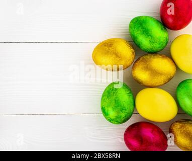 Uova di pasqua colorate su sfondo bianco di legno, spazio libero per il testo Foto Stock