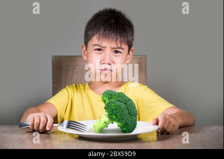 8 anni disgustato e dispiaciuto bambino rifiutando di mangiare sano verde broccoli sensazione di sconvolto in educazione alimentare bambino su cibo sano fresco e y Foto Stock