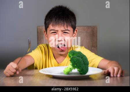 8 anni disgustato e dispiaciuto bambino rifiutando di mangiare sano verde broccoli sensazione di sconvolto in educazione alimentare bambino su cibo sano fresco e y Foto Stock