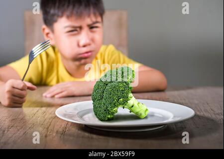 8 anni disgustato e dispiaciuto bambino rifiutando di mangiare sano verde broccoli sensazione di sconvolto in educazione alimentare bambino su cibo sano fresco e y Foto Stock