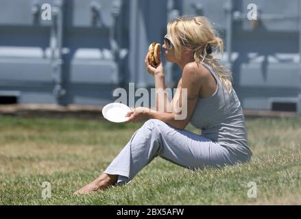 Pamela Anderson seduta sull'erba, mangiando hamburger a Malibu, CA maggio 2008 Foto Stock