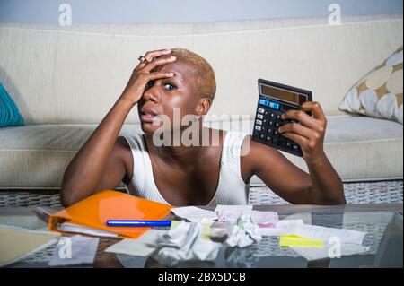 Donna afro americana nera disperata e stressata con calcolatore e cartwork banking in stress contabilità business finanza fiscale e pagamenti in finan Foto Stock