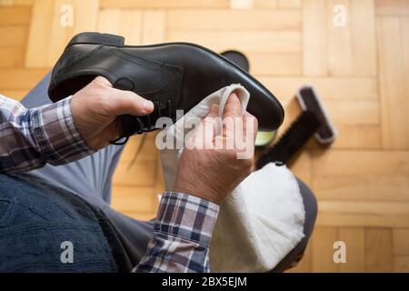 Uomo mani pulire le sue scarpe con uno straccio e cera di scarpa per migliorare le condizioni delle sue scarpe, scarpe di lucidatura Foto Stock
