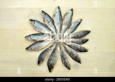 Fiancheggiata pesce secco modello su una superficie di legno. Tessuto di fondo del prodotto di pesce secco. Foto Stock