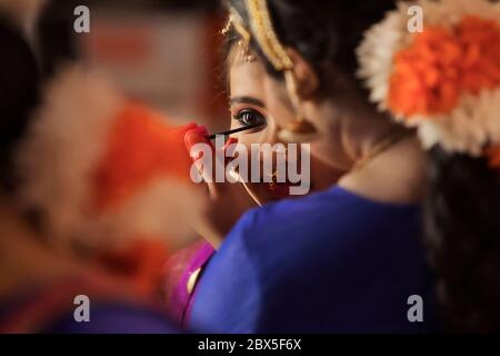 Ballerina di Bharatnatyam che applica il kajal agli occhi del suo allievo. Foto Stock