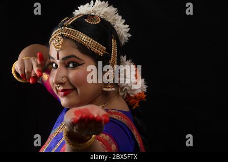 Ballerina Bharatnatyam che offre una bella performance di fronte a uno sfondo scuro. Foto Stock