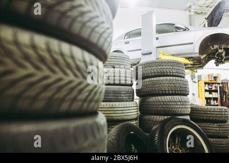 Vista per il servizio di auto, un sacco di ruote pronte per il cambio e la vettura sul martinetto idraulico, centro di assistenza auto Foto Stock