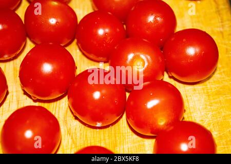 Piccoli pomodori ciliegini rossi su una tavola di legno. Primo piano Foto Stock