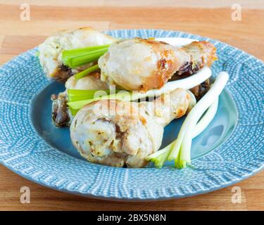 Pollo appetitoso con cipolle verdi. Bastone di pollo fritto in un piatto. Serve piatti. Foto Stock