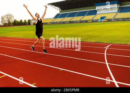 Happy athlete ha vinto la gara di stadio. Vincitore dello sport Foto Stock