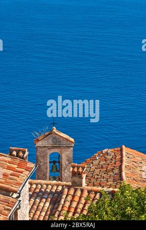 Tetti in piastrelle di terracotta e campanile del Villaggio di Eze con il Mar Mediterraneo. Costa Azzurra, Alpi Marittime (06), Francia Foto Stock