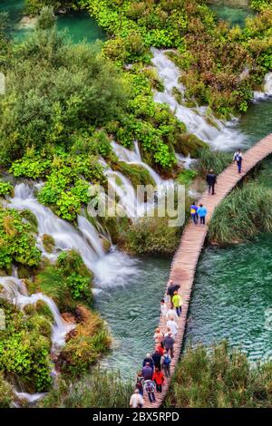 Plitvice Lakes National Park in Croazia, persone, gruppo di turisti su un percorso in legno attraverso il lago con numerose cascate d'acqua, cascate, vie aeree Foto Stock