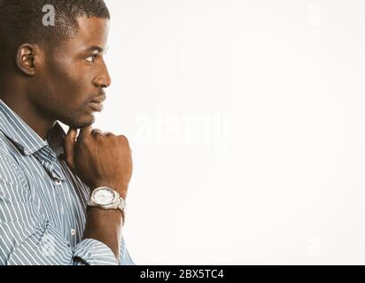 Un uomo d'affari afro-americano pensivo tocca il mento con una mano con un orologio da polso di lusso. Un ragazzo creativo che genera idee su sfondo bianco. Copia Foto Stock