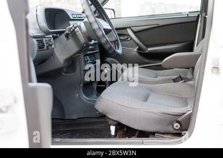 Sedili anteriori in tessuto grigio per conducente e passeggero con pannello di controllo nero e console centrale con volante in plastica e maniglie in una vecchia Rus Foto Stock