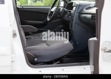 Una portiera anteriore aperta per il passeggero di una vecchia auto russa bianca con sedili rivestiti in tessuto grigio e con un pannello di controllo in plastica nera, un interno pulito a poppa Foto Stock