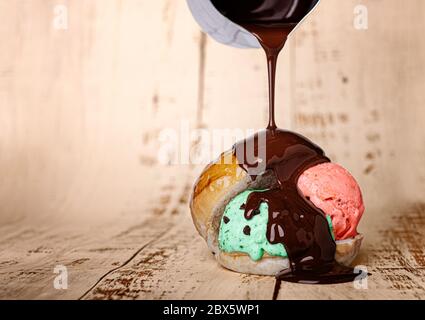 palla di gelato alla fragola e alla menta all'interno di un panino di pane al latte, che gocciola cioccolato liquido Foto Stock