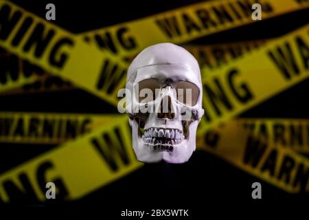 Pericoloso cranio umano sopra il nastro di avvertimento giallo Foto Stock