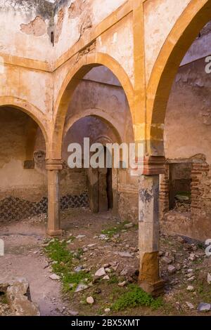 Uno dei molti cantieri in una casa abbandonata. Arcade con archi su colonne. Erba e crescere nelle rovine. Dar Caid Hadji (usato anche Hajji), Marocco. Foto Stock